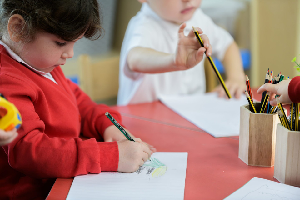 Children drawing with pencils at a classroom table