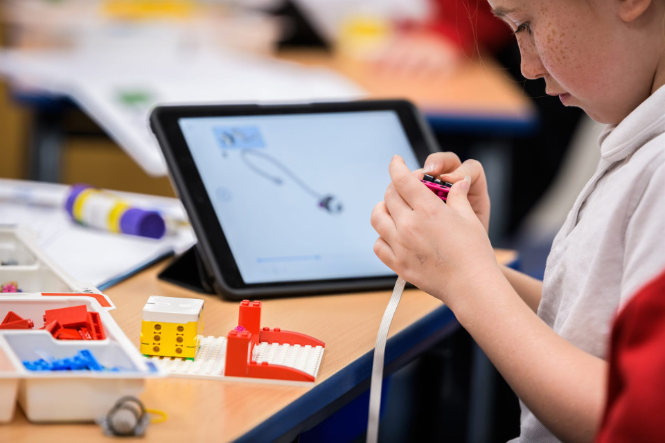 A pupil programming a model with a tablet
