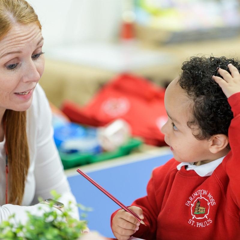 A teacher helping a young pupil with his drawing