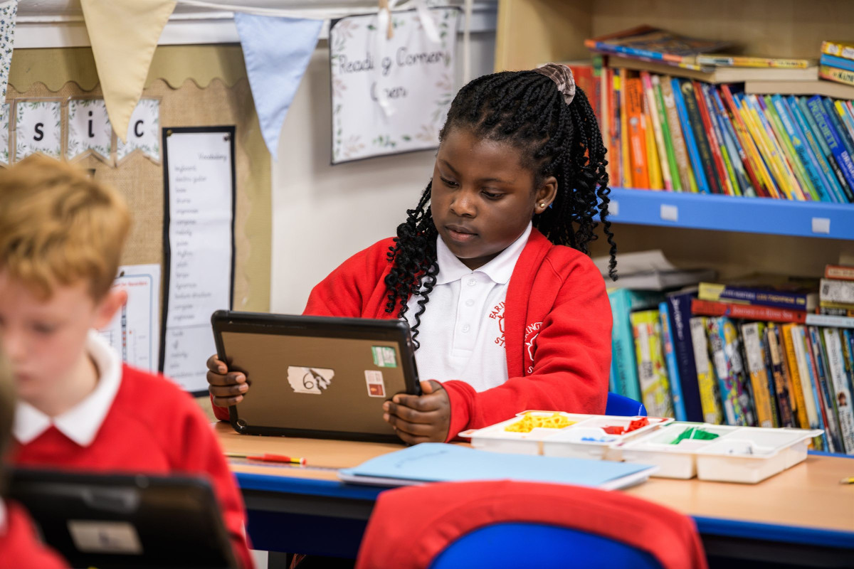 A pupil using a tablet in the classroom library