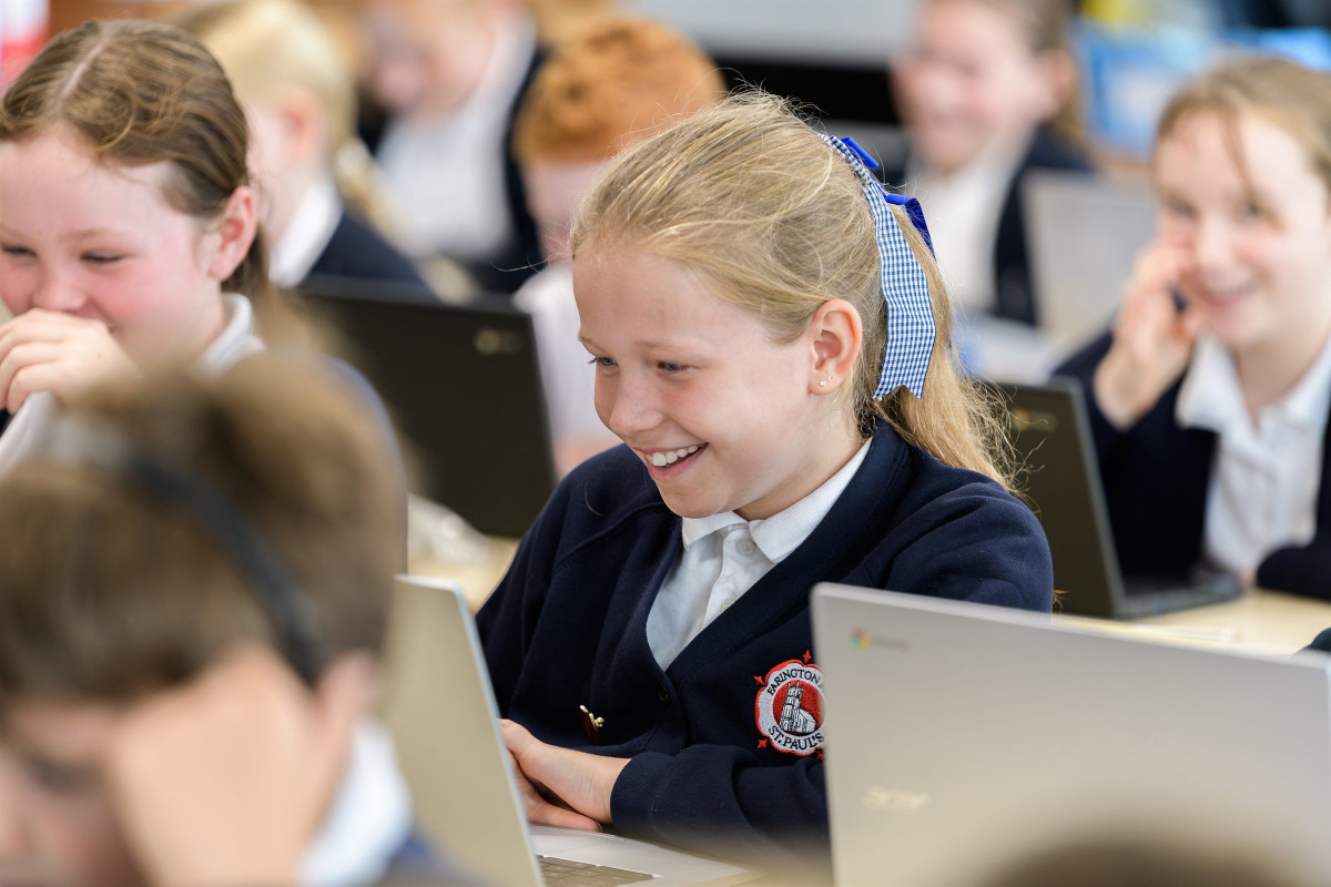 A smiling pupil working on a laptop
